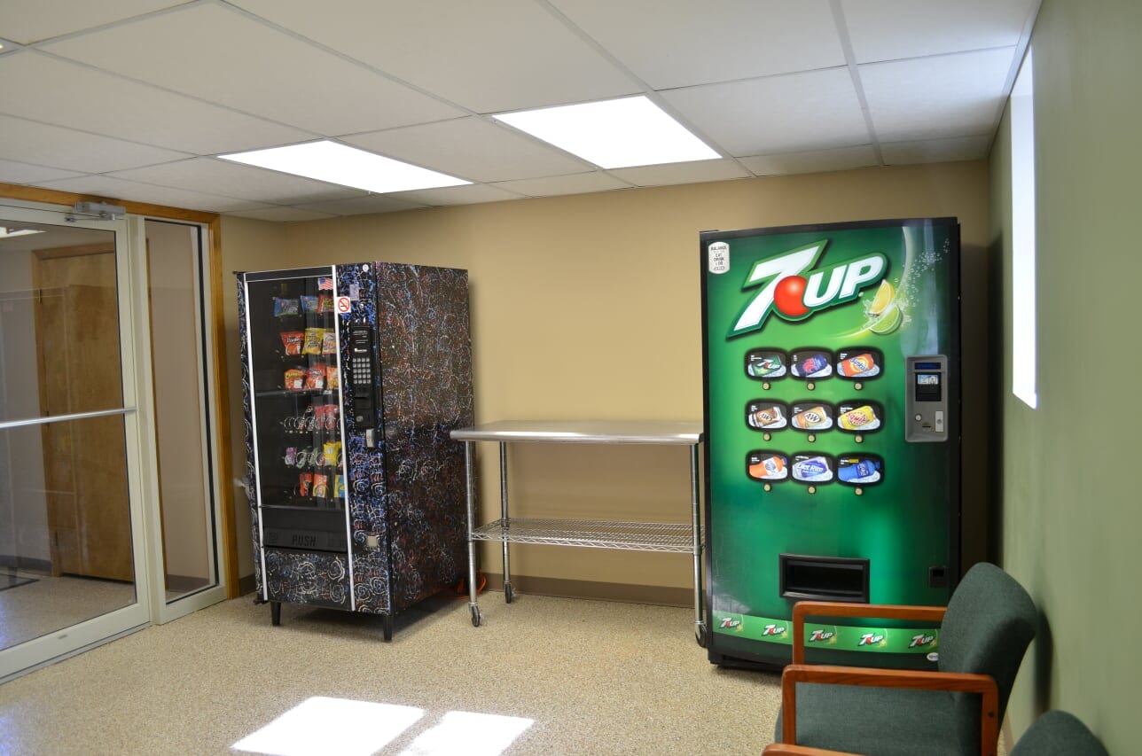 A vending machine and some tables in a room.