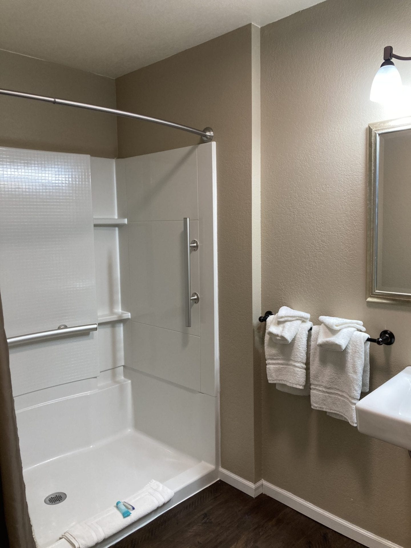 A bathroom with a shower, sink and mirror.